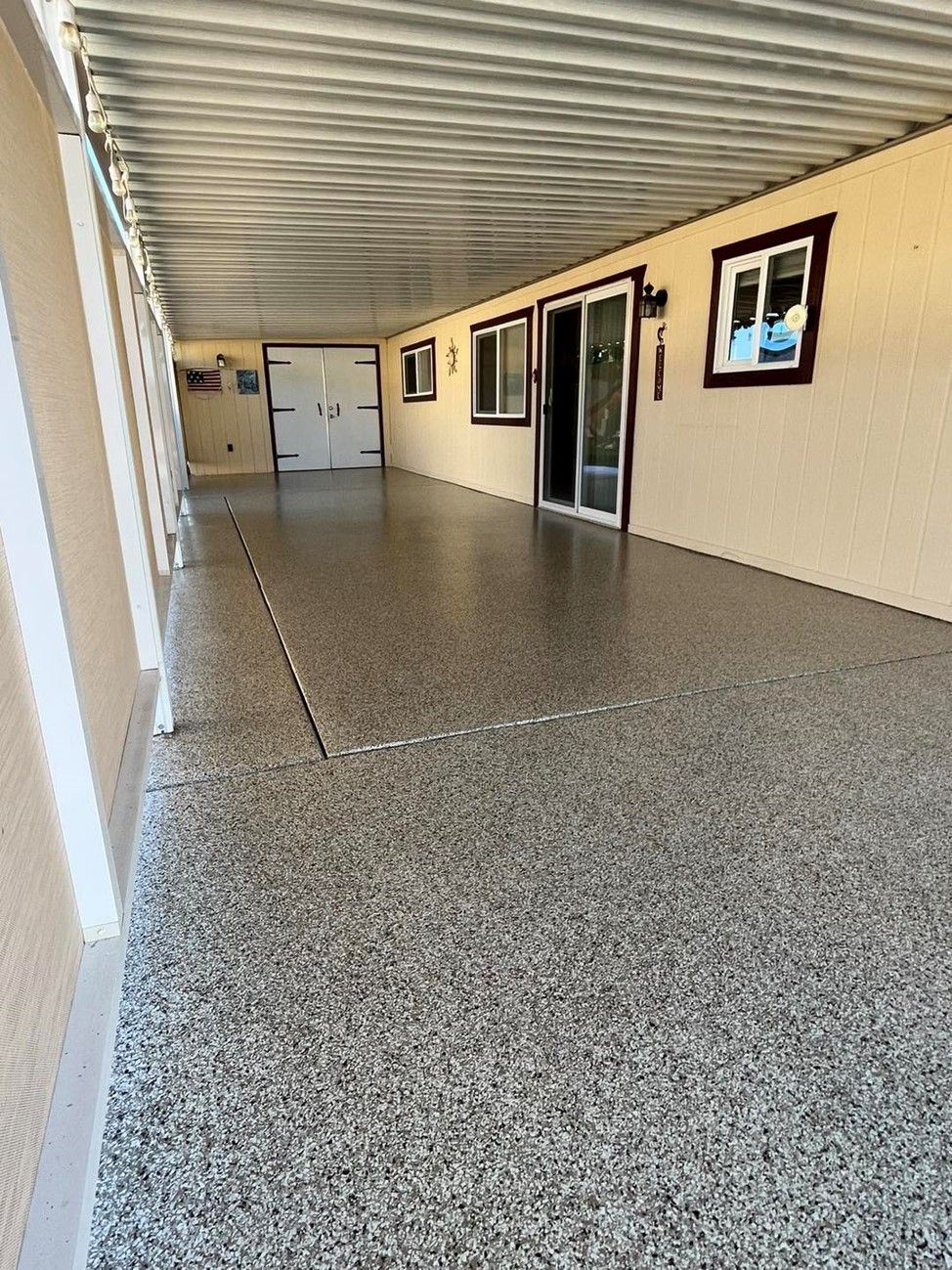 A long hallway with a concrete floor and a garage door.