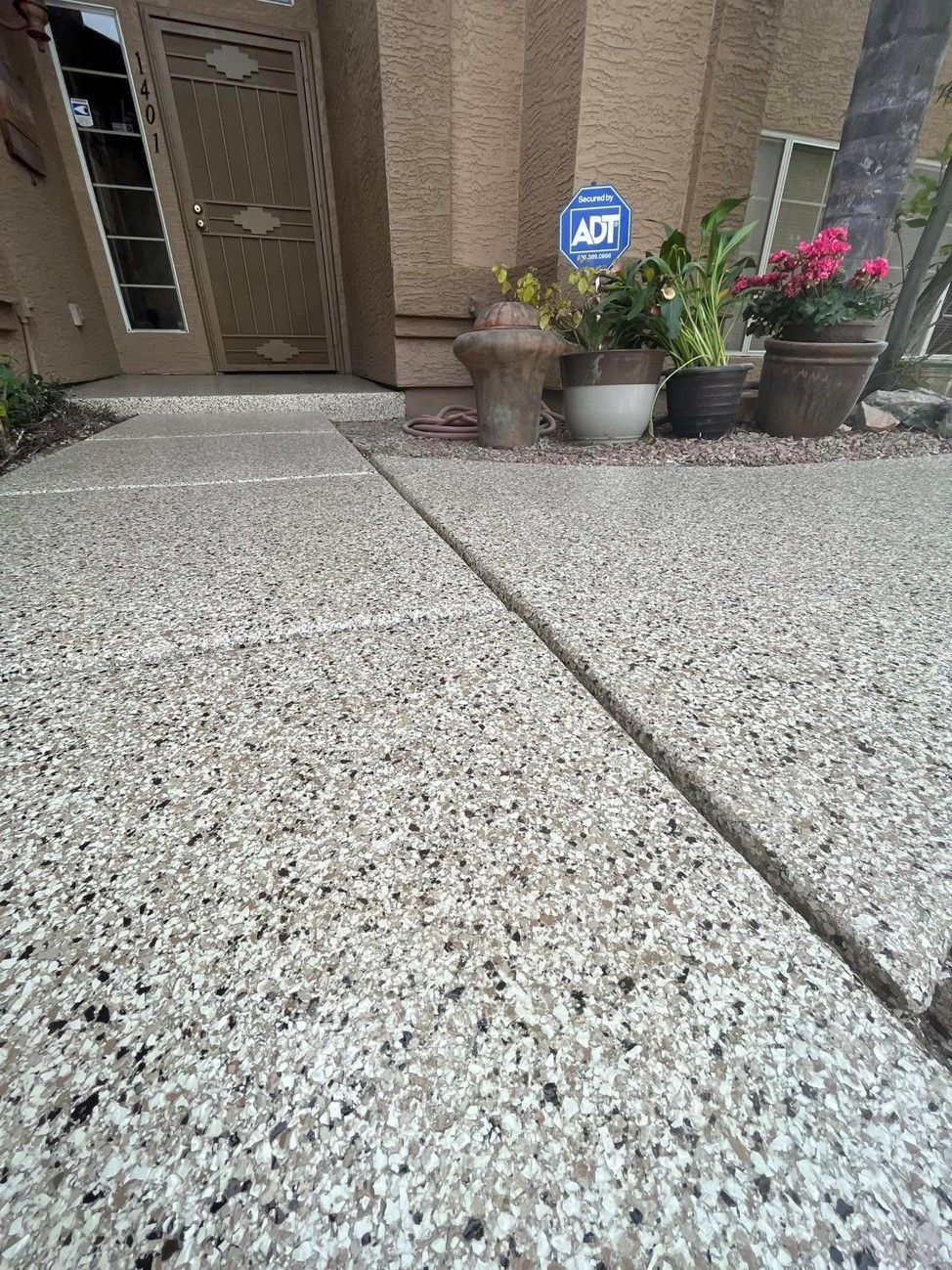 A concrete driveway with potted plants in front of a house.