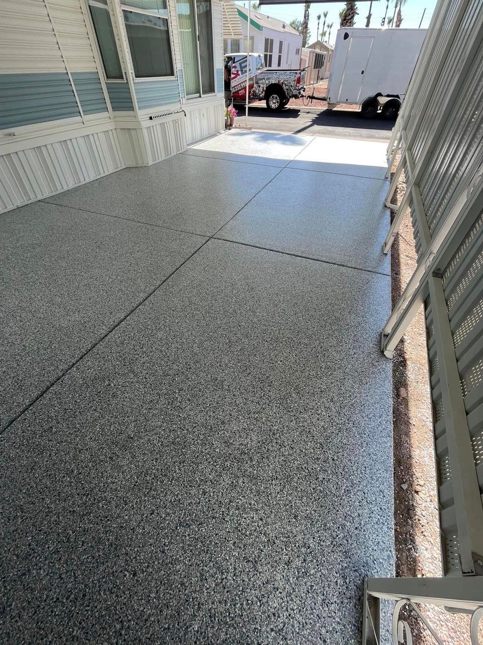 A concrete porch with a trailer parked in the background.