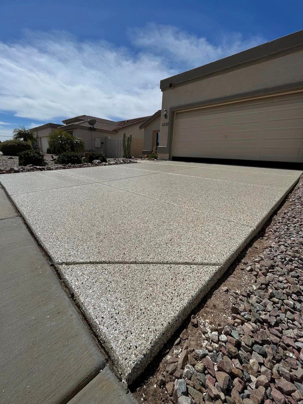 A concrete driveway with a garage in the background