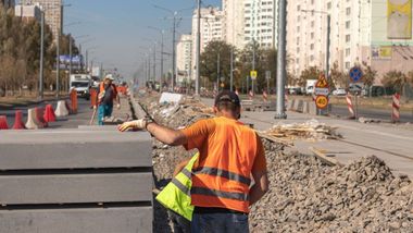 A Couple Of Construction Workers Are Walking Down A Street