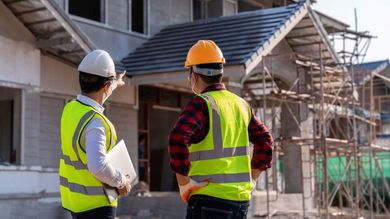 A Couple Of Construction Workers Are Walking Down A Street