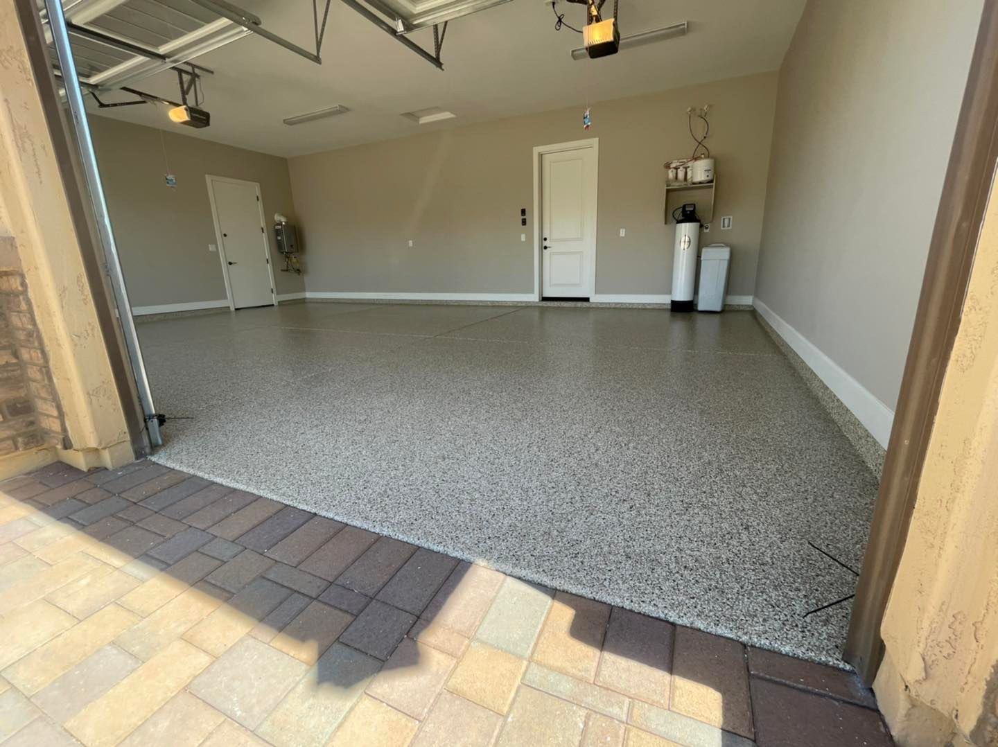 A garage with a concrete floor and a garage door open.