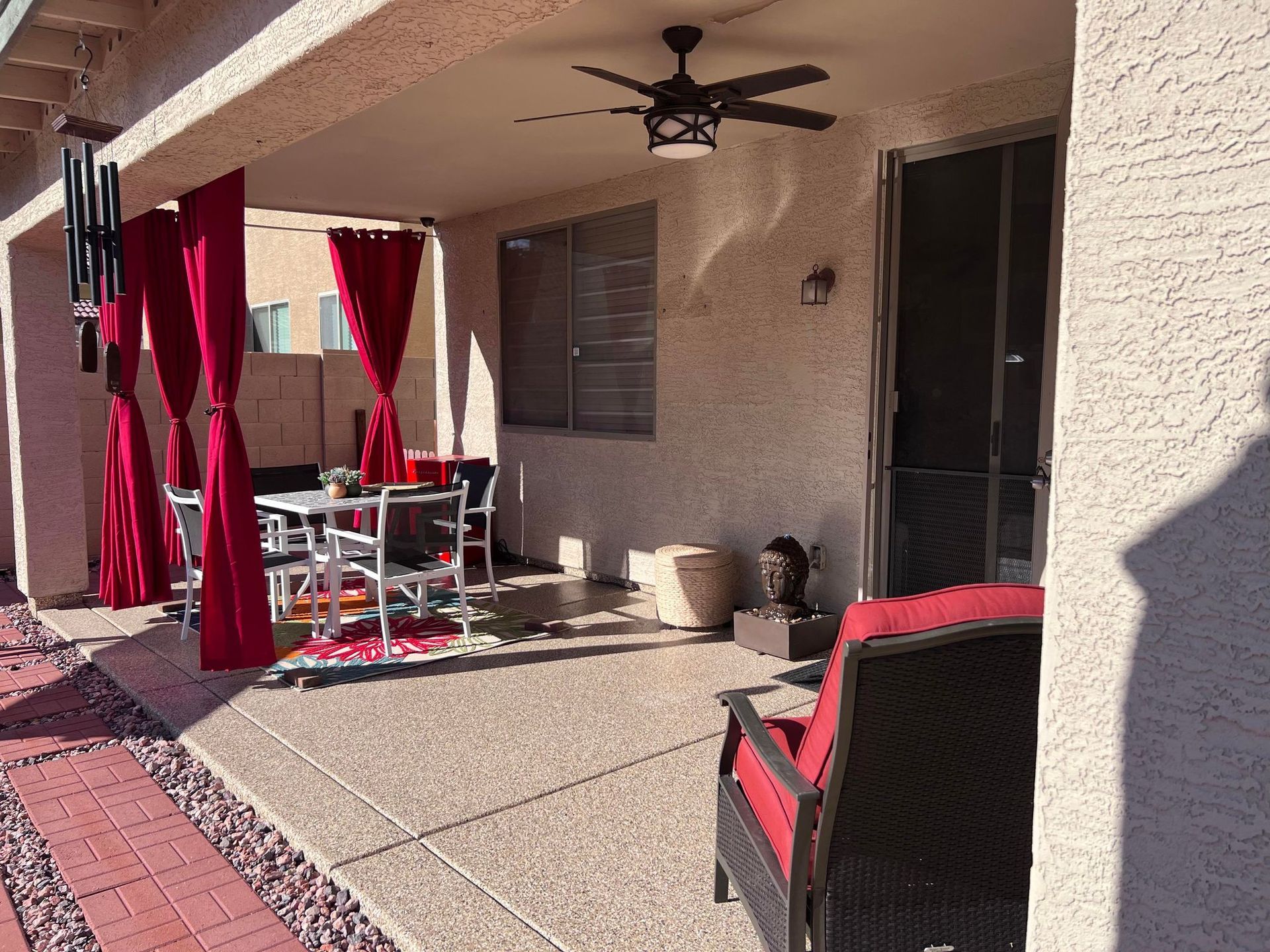 A patio with red curtains and a ceiling fan.
