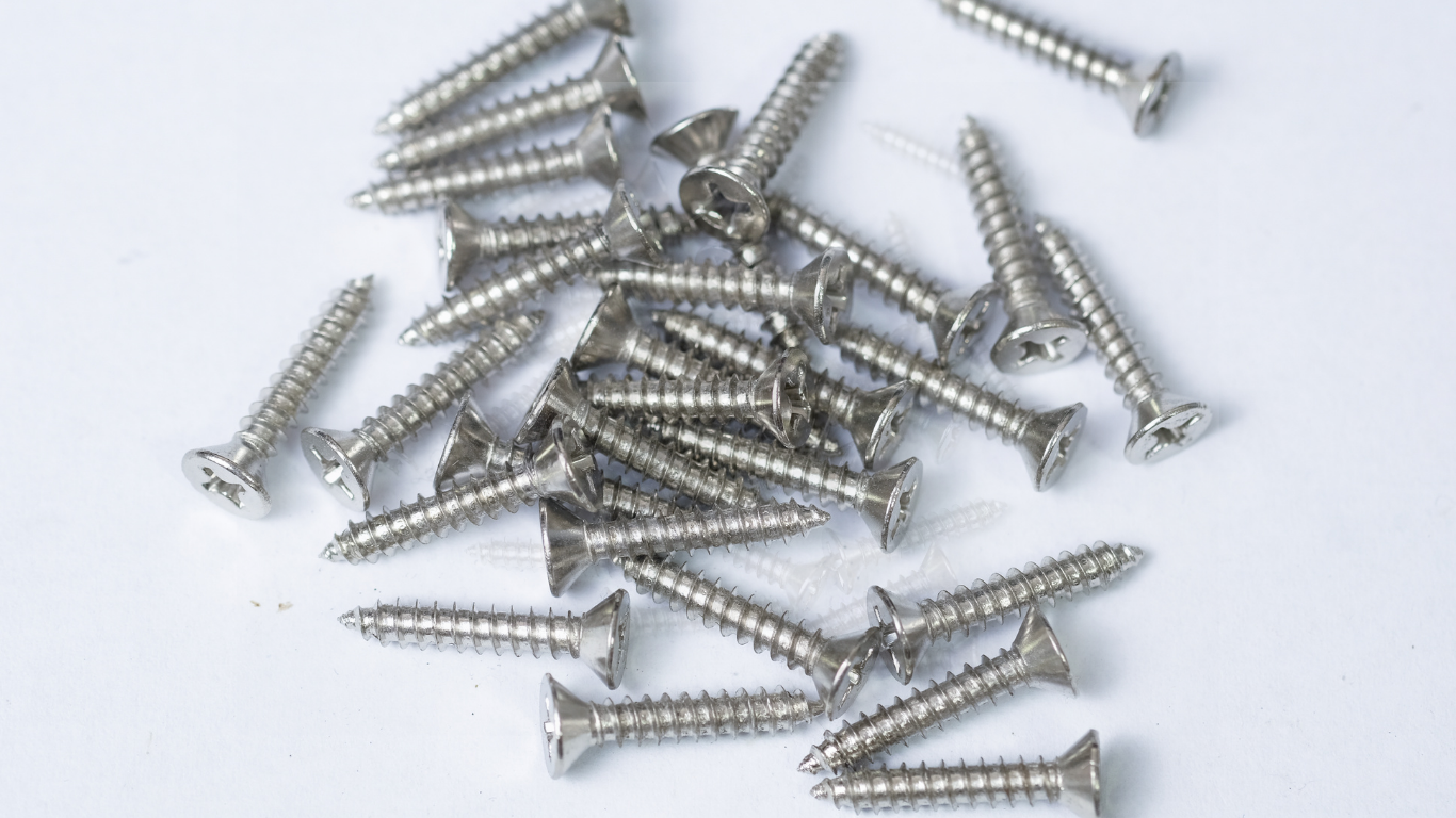 Pile of silver screws on a white surface.