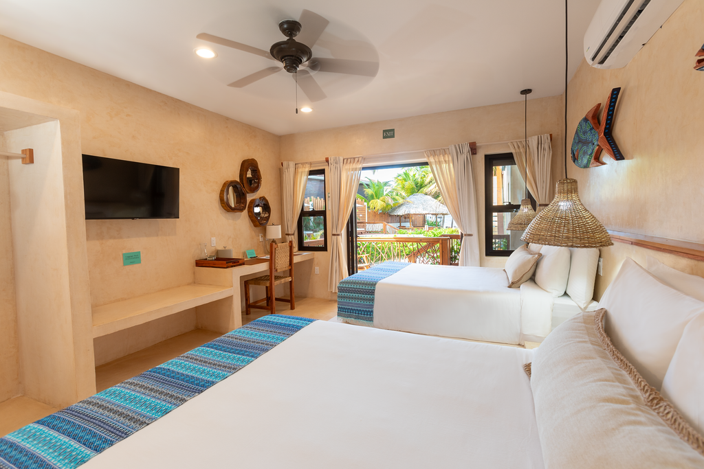 A hotel room with two beds , a flat screen tv and a ceiling fan.