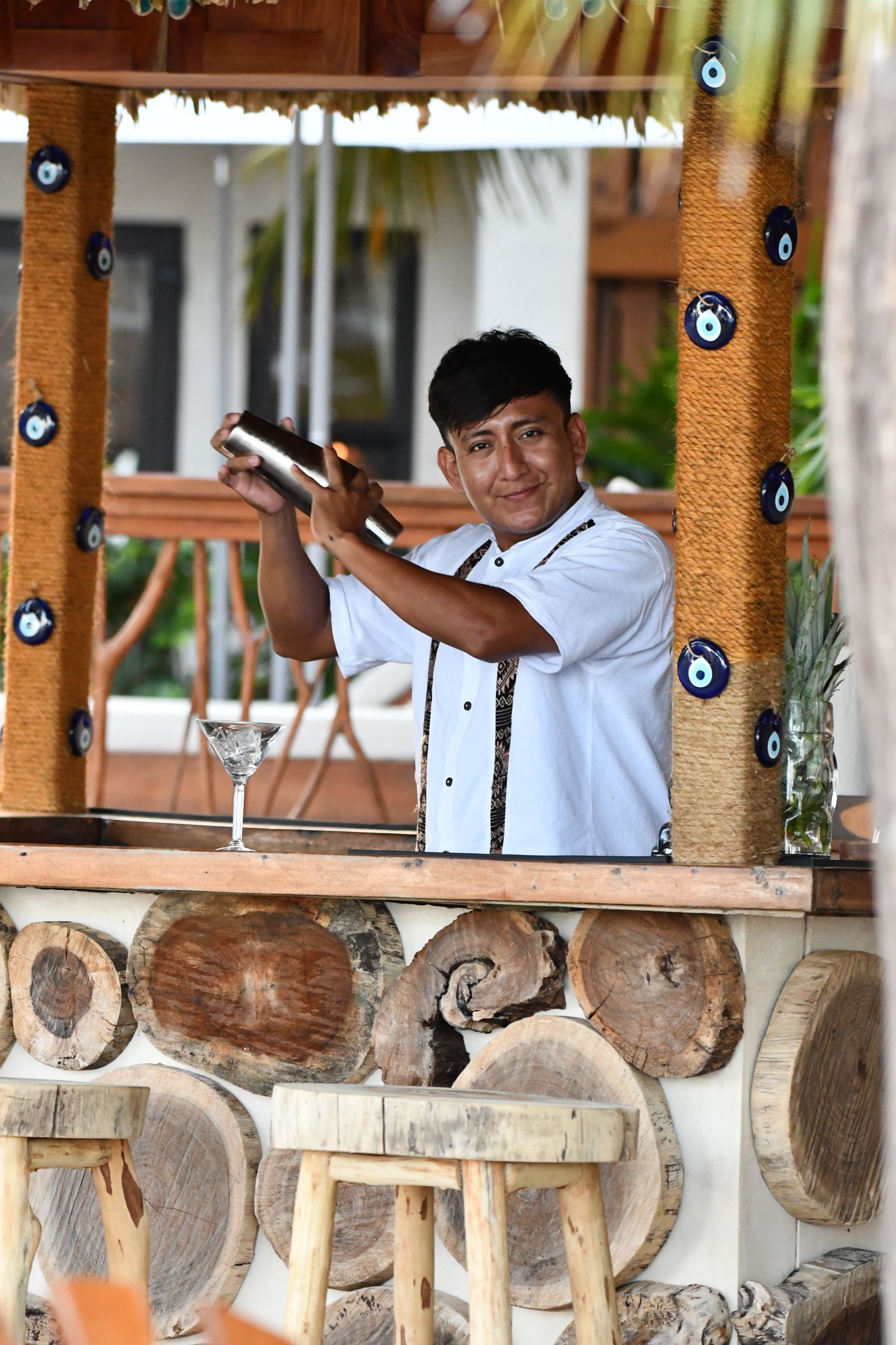 A man is standing behind a wooden bar making a drink.