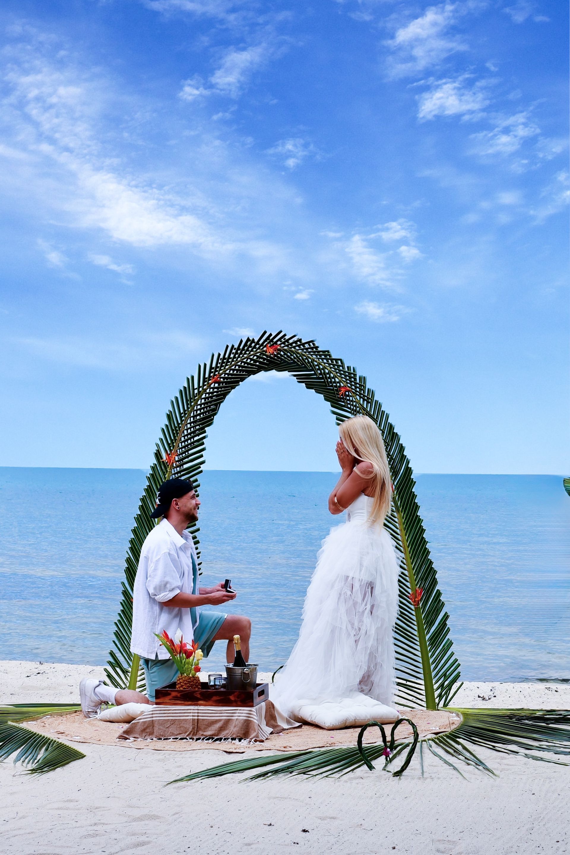 A man is proposing to a woman on the beach.