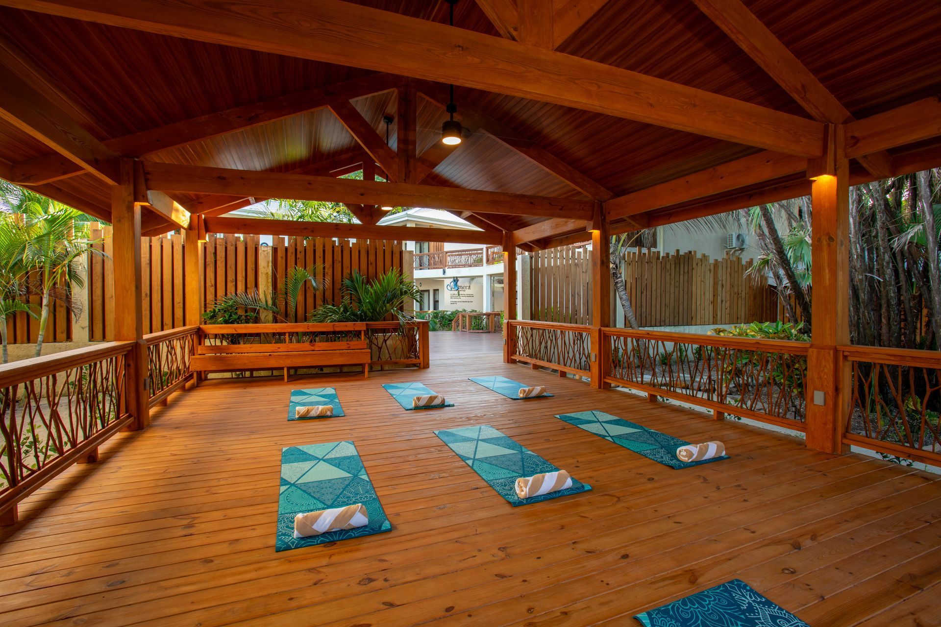 Person holding a tray of food on a beach; tray includes fruit, beans, corn, and pastries.