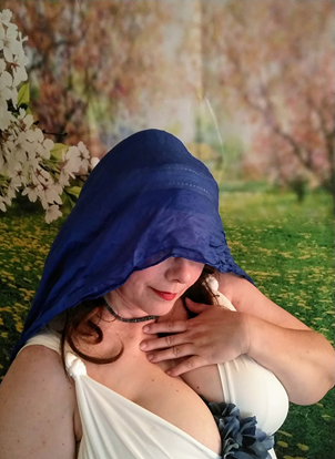 A woman in a white dress with a blue scarf over her head