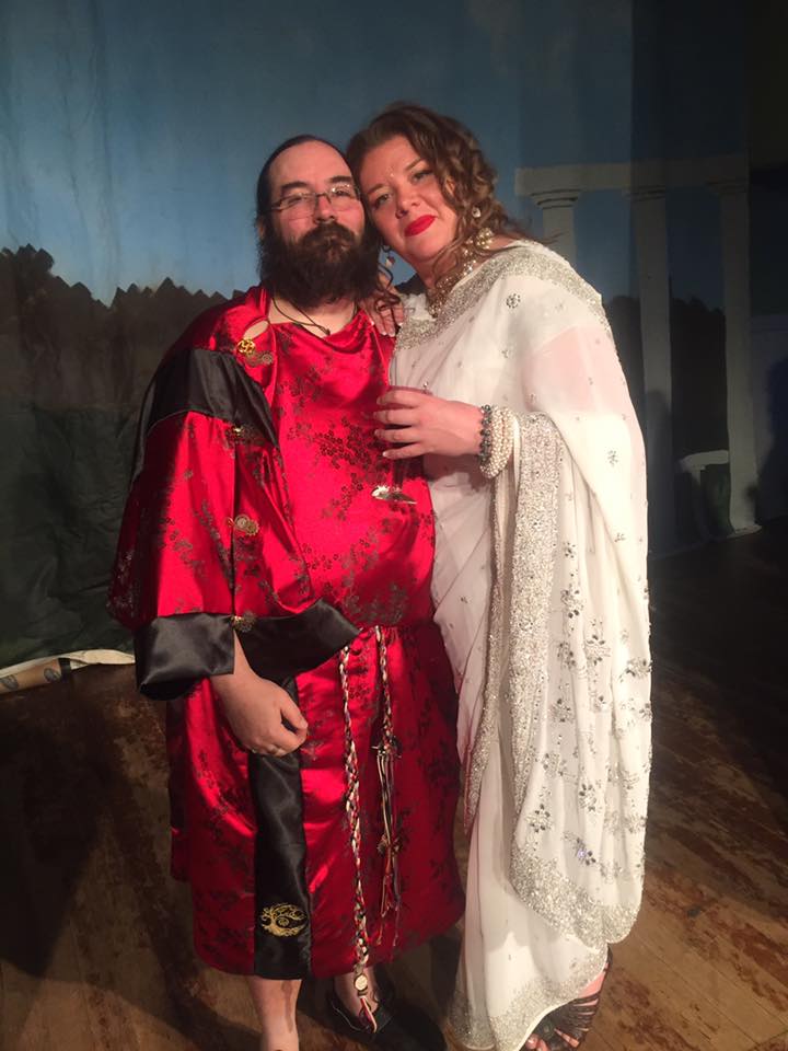 A man in a red robe and a woman in a white dress are posing for a picture.