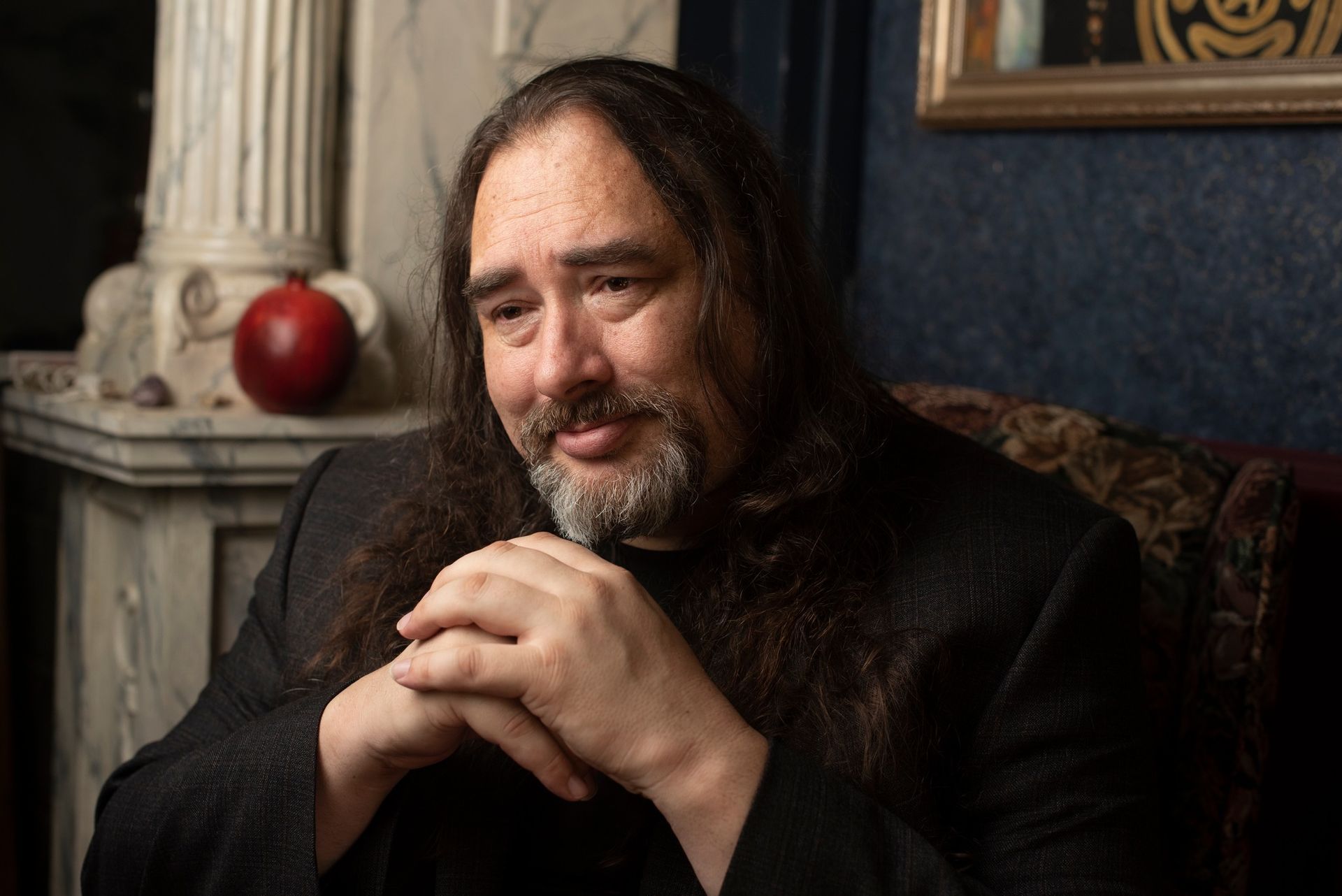 A man with long hair and a beard is sitting on a couch with his hands folded, Darrell Delph.