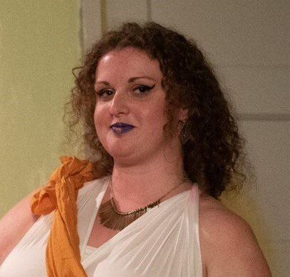 A woman with curly hair is wearing a white dress and a necklace, representing Euphrosyne.