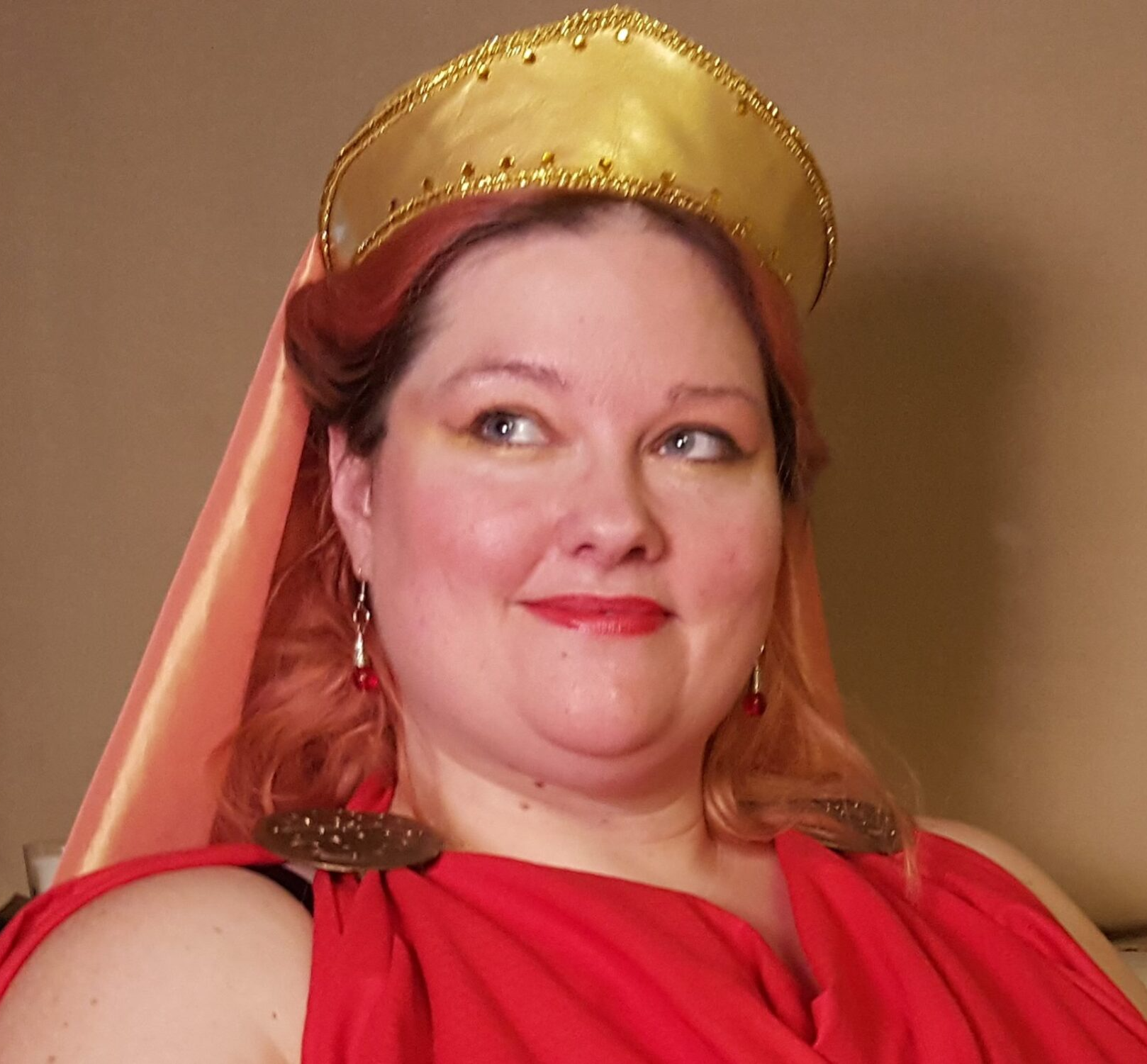 A woman wearing a red dress and a gold crown. representing Hestia.