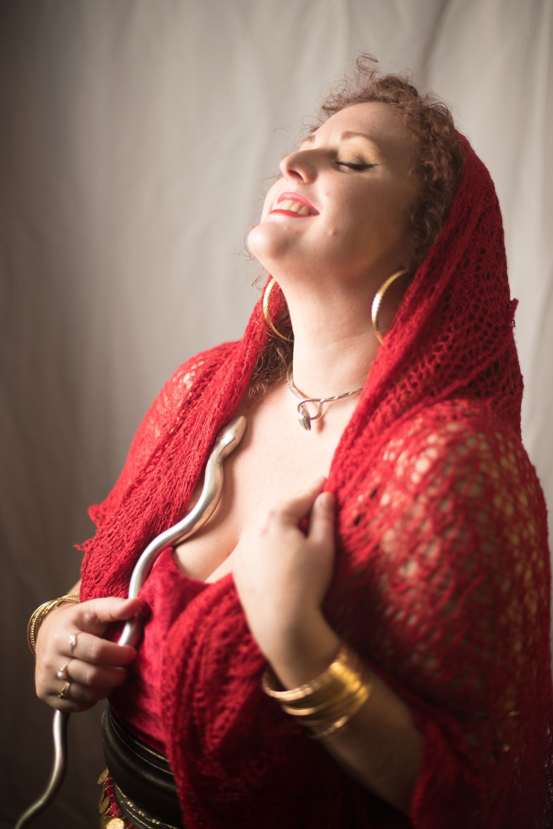 A woman in a red dress is holding a white snake.