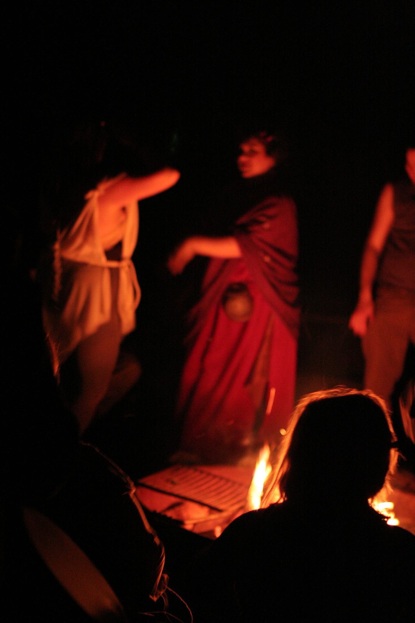 People dressed in robes, dancing around a fire at Spring Mysteries.