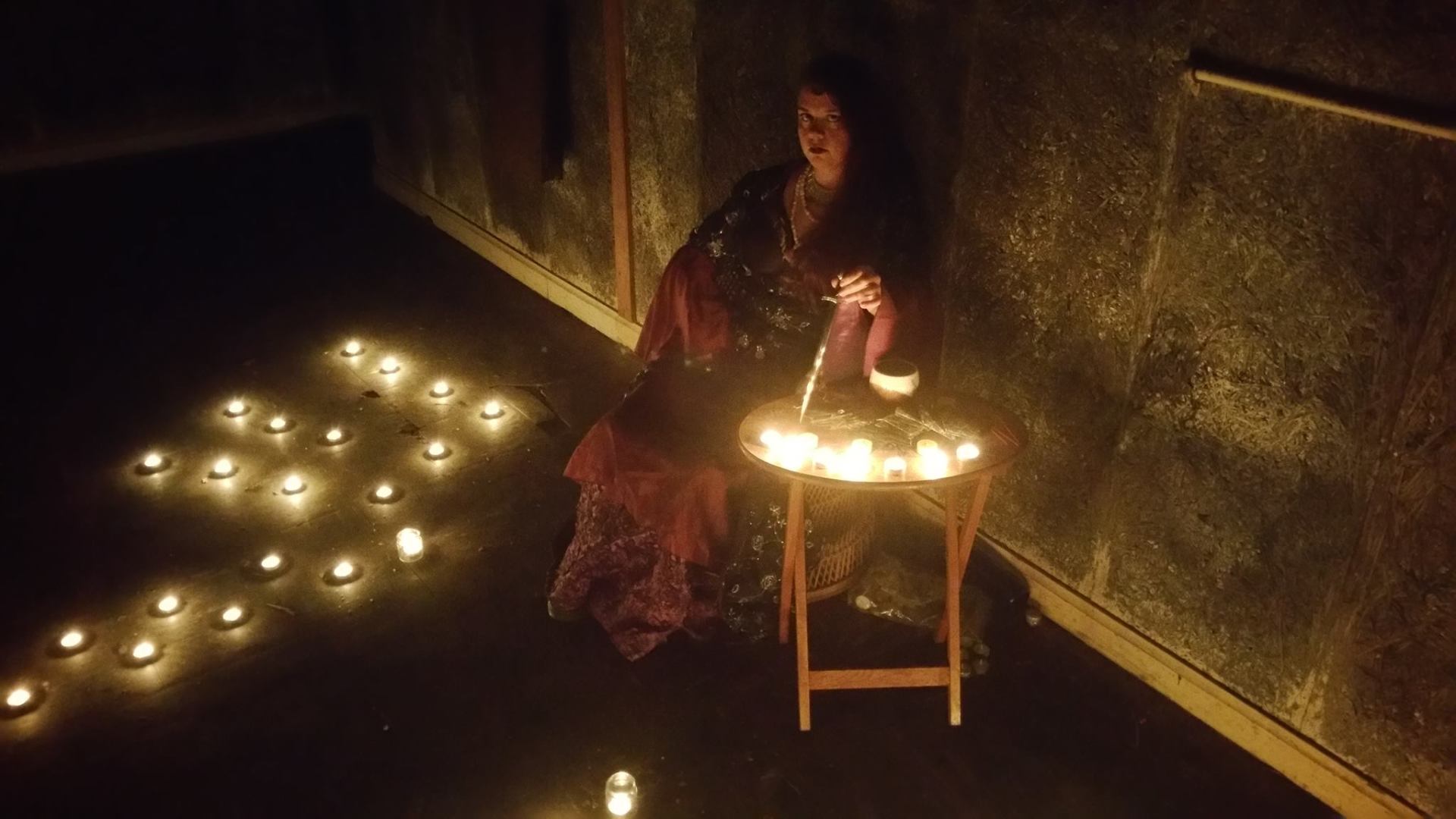 A woman is sitting at a table with candles on the floor.