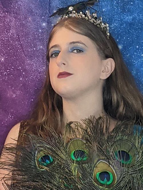 A woman wearing a tiara and holding peacock feathers, Rebecca Minty Delph representing Hera.