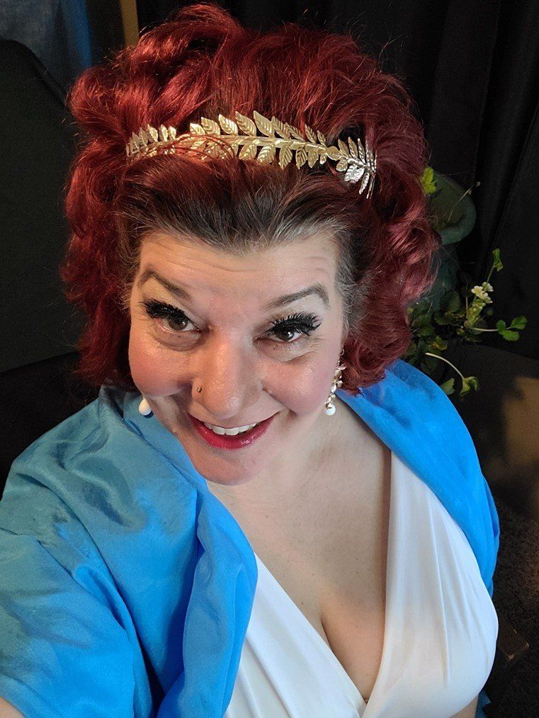 A woman with red hair is wearing a headband and smiling, Isabel De Fleur.
