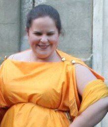 A woman is wearing a yellow dress and smiling, representing Euterpe.