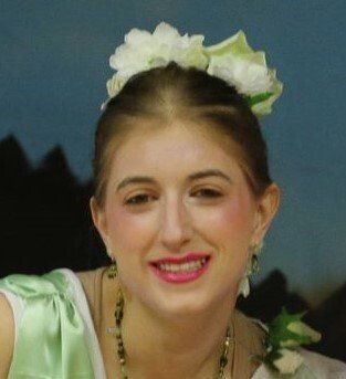 A woman with flowers in her hair is smiling for the camera Rebecca Minty Delph