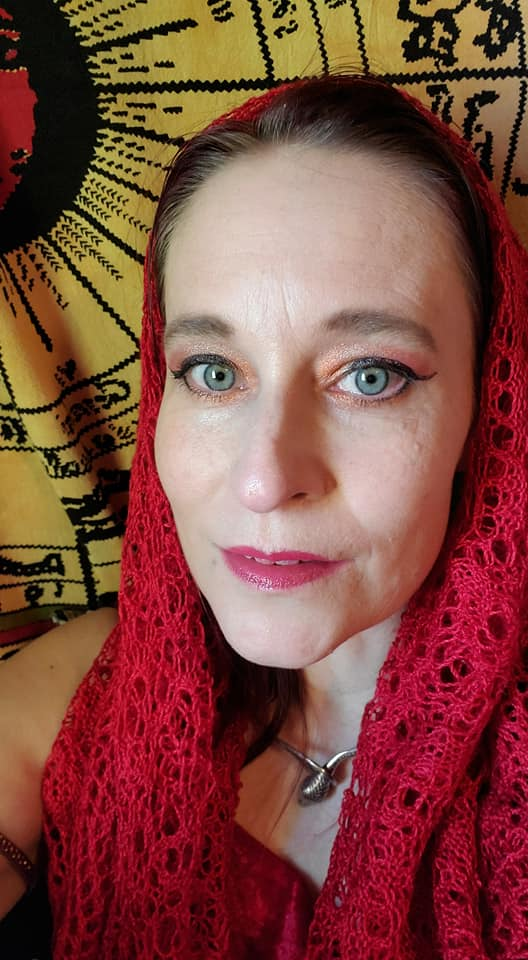 A woman is wearing a red scarf around her head, representing Pythia.