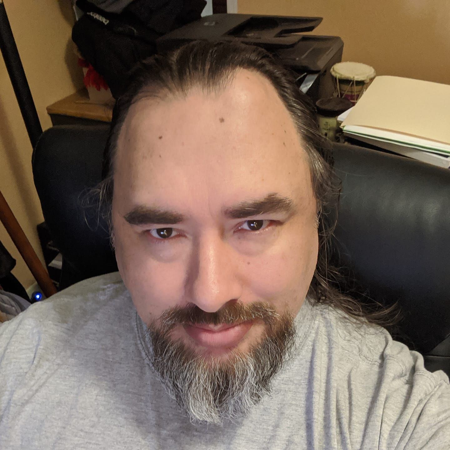 A man with long hair and a beard is wearing a sunflower shirt.