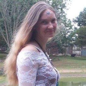 A woman with long hair is wearing a white lace top.