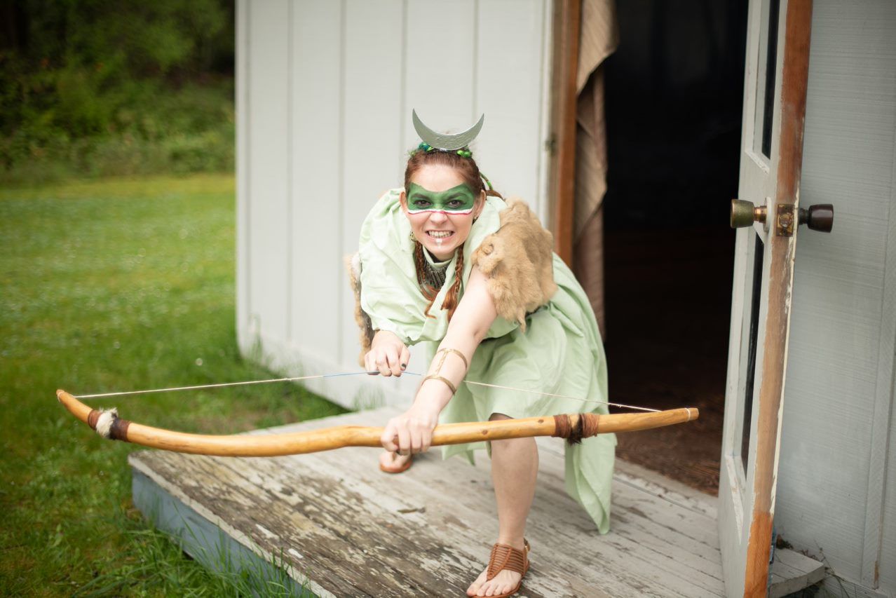 A woman in costume holding a bow, Titania Thunderlily representing Artemis.
