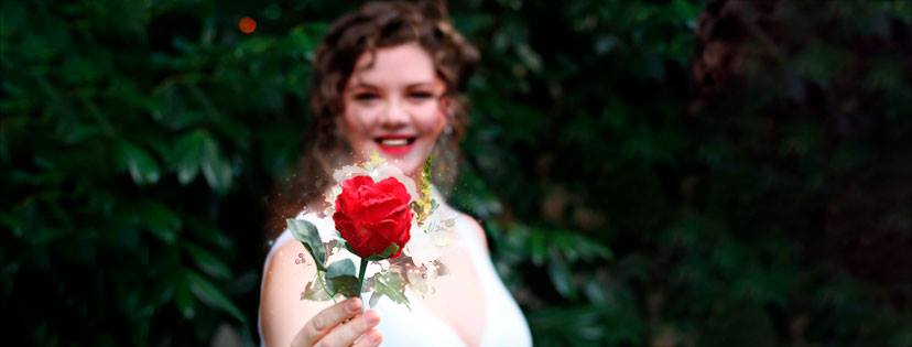 A woman in a white dress is holding a red rose in her hand, representing Aphrodite.