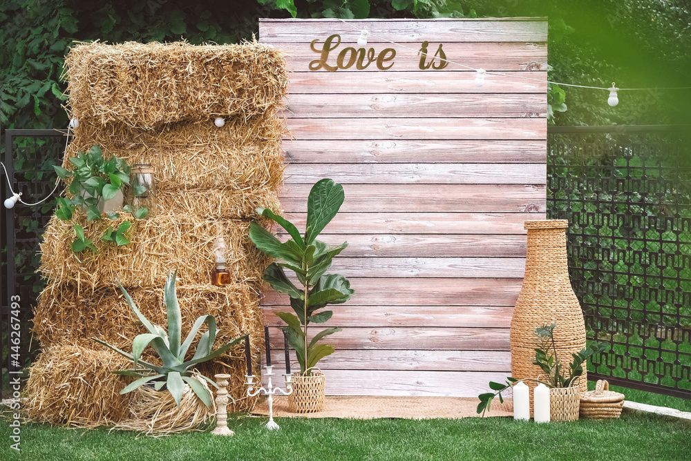 a wooden wall with hay bales and plants in front of it .
