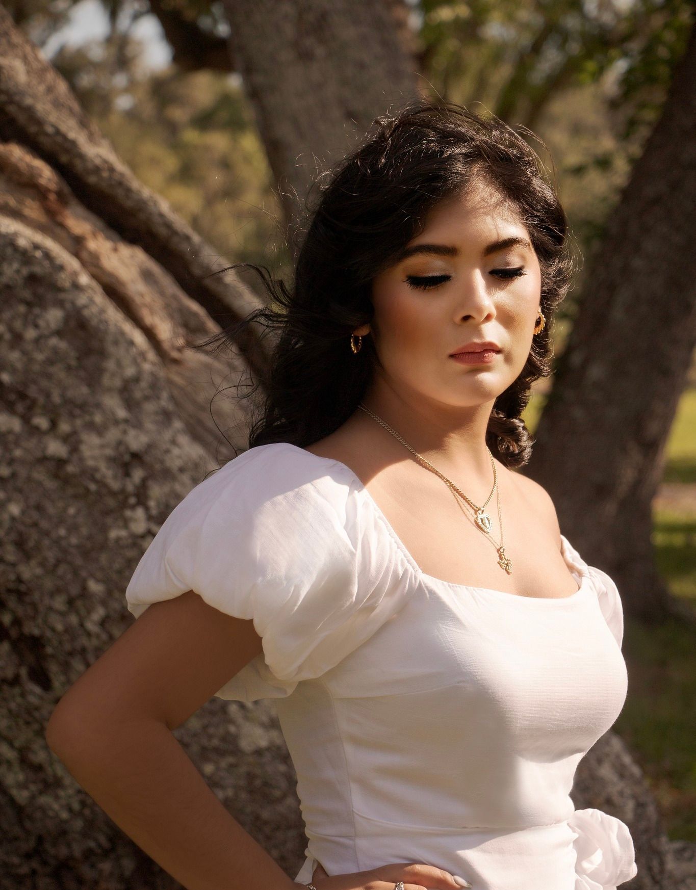 a woman in a white dress is leaning against a tree