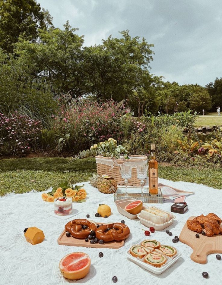 a picnic in a park with food and drinks on a blanket .