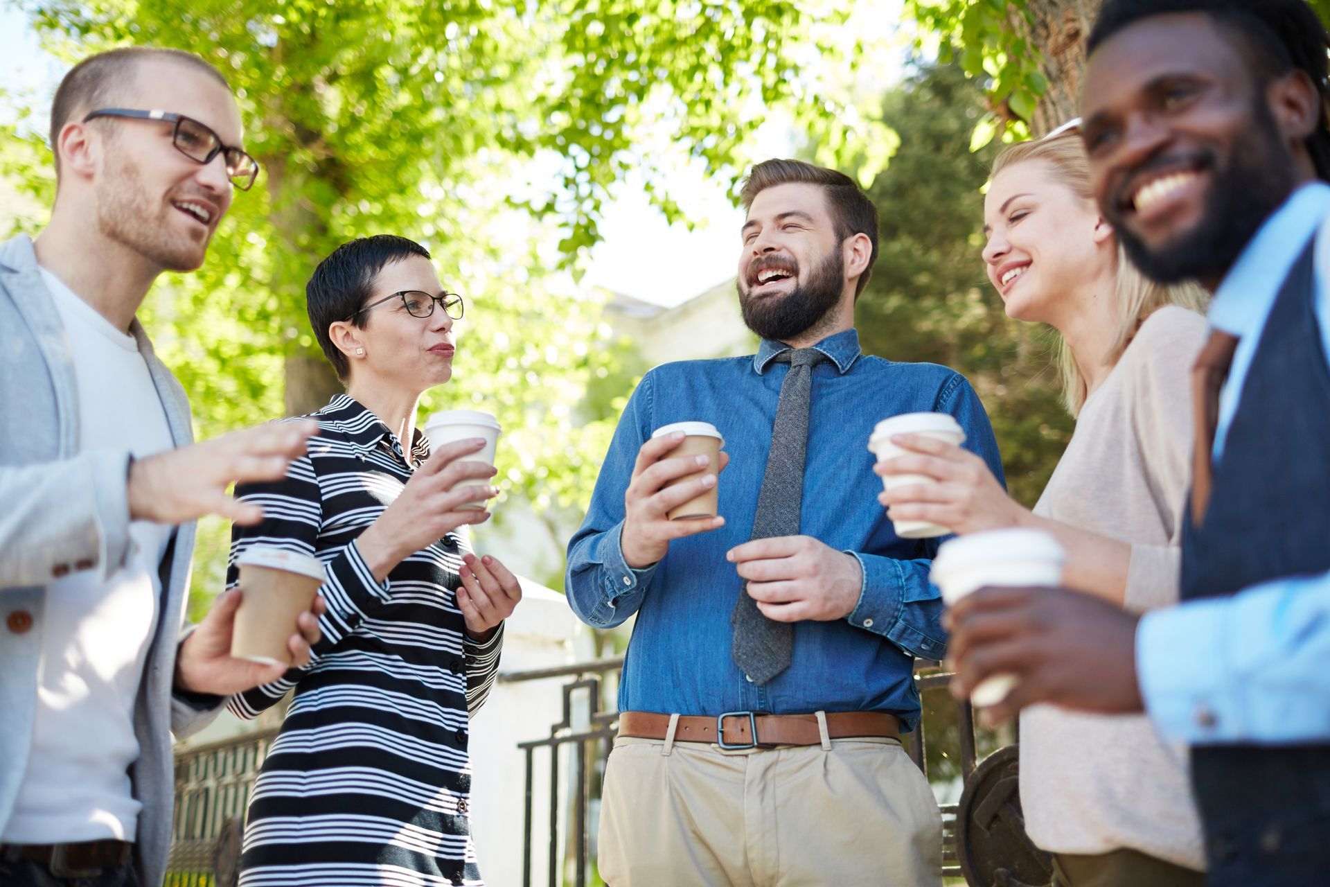 a group of people are standing next to each other holding cups of coffee .