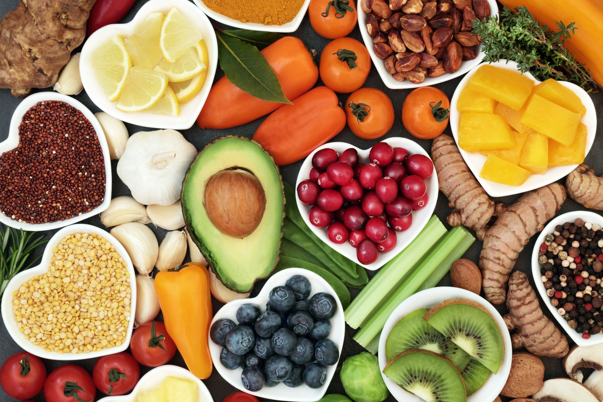 a variety of fruits and vegetables in heart shaped bowls on a table .