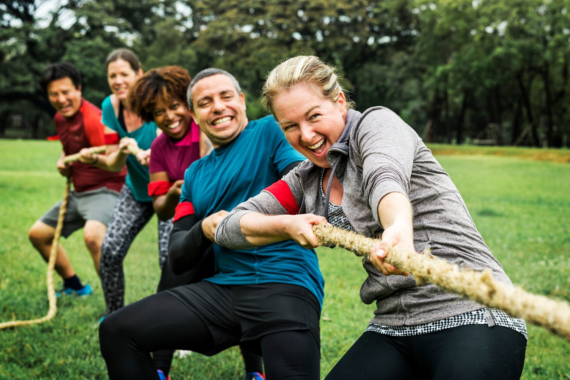 5 people laughing having fun playing tug of war