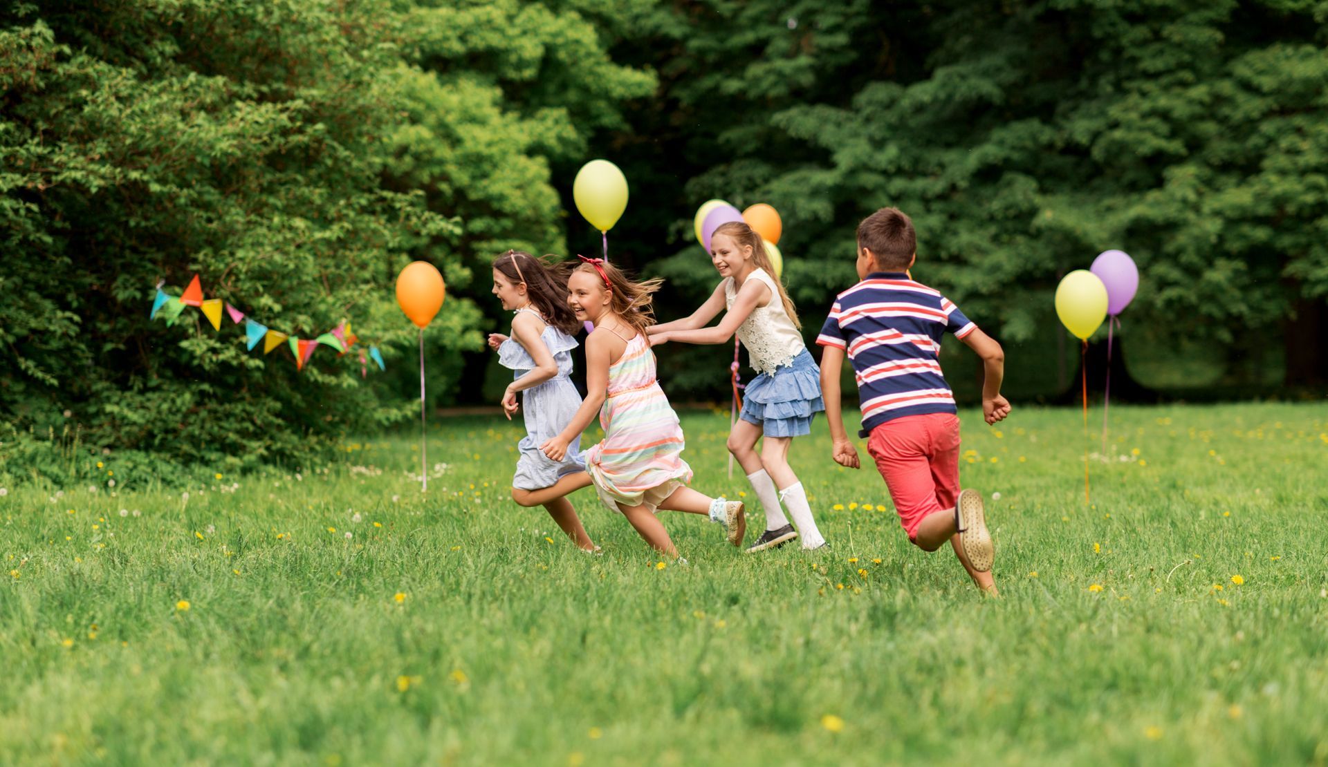 a group of children are playing with balloons in a park .