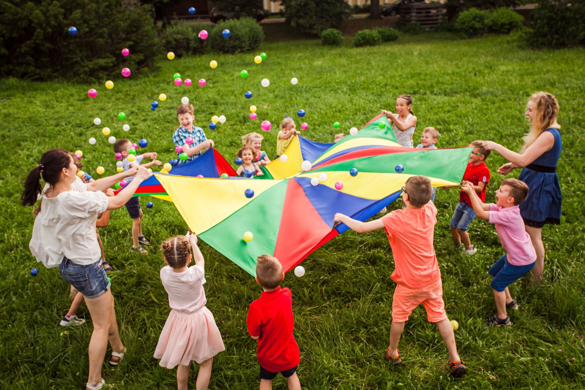a group of children are playing with a parachute in a park .