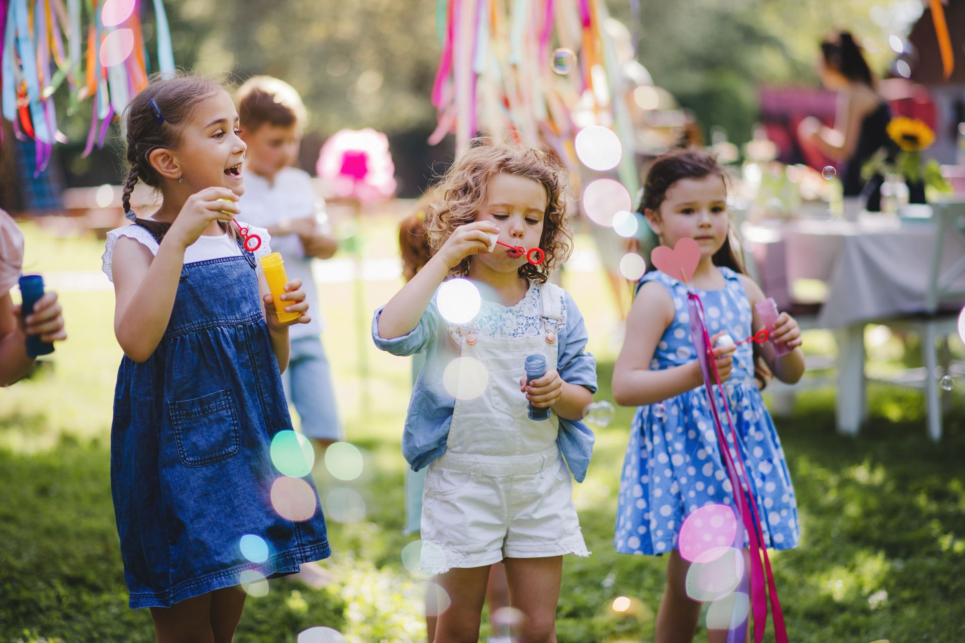 a group of young girls are blowing soap bubbles at a birthday party .