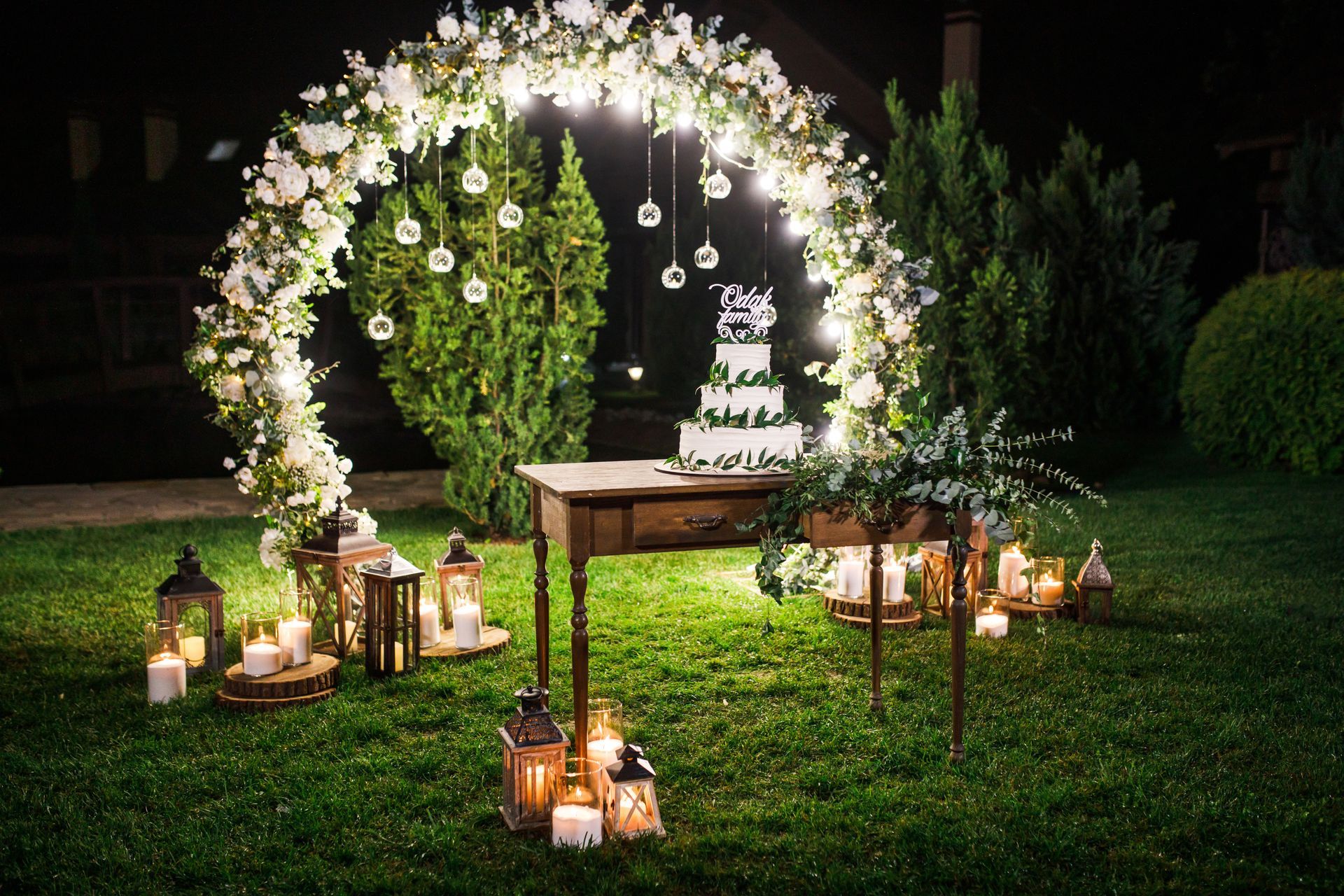 a wedding cake is sitting on a table under a floral arch .