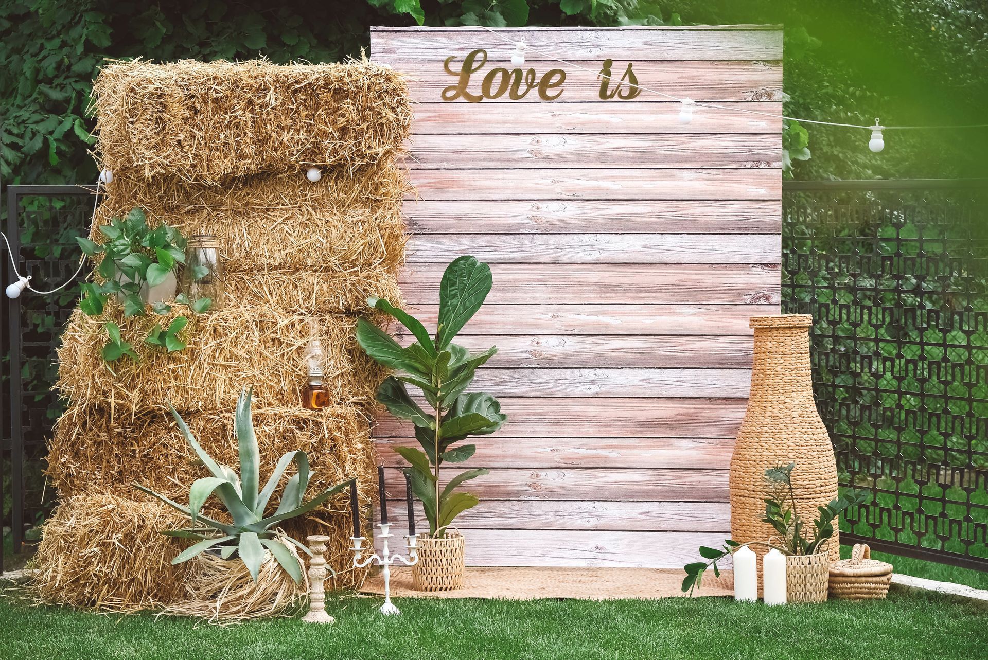 a wooden wall with hay bales and plants in front of it .