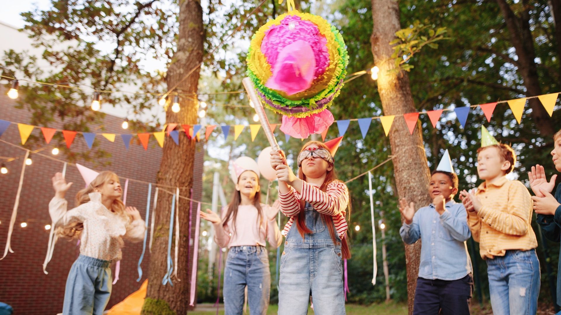 a group of children are playing with a pinata at a birthday party .