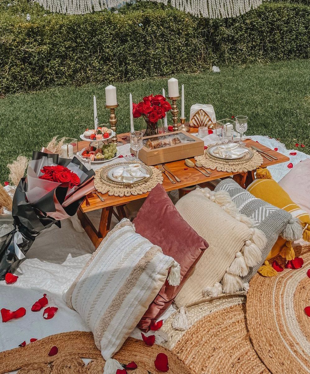 a picnic table with plates , candles , and flowers on it in the grass .