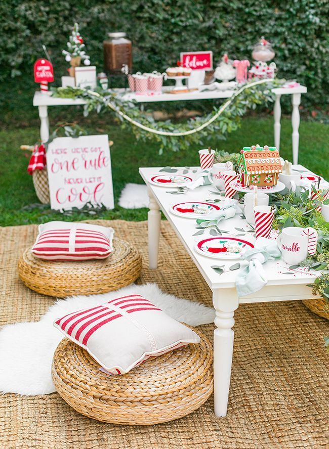 a table set up for a christmas party with a gingerbread house in the background .