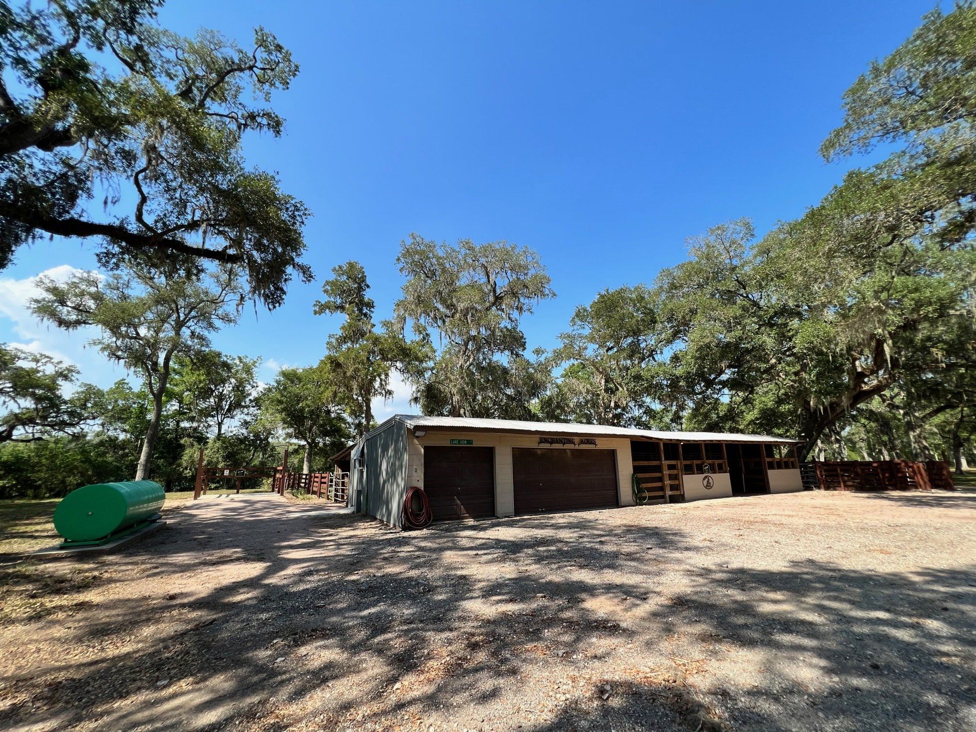 a horse stable is surrounded by trees on a sunny day