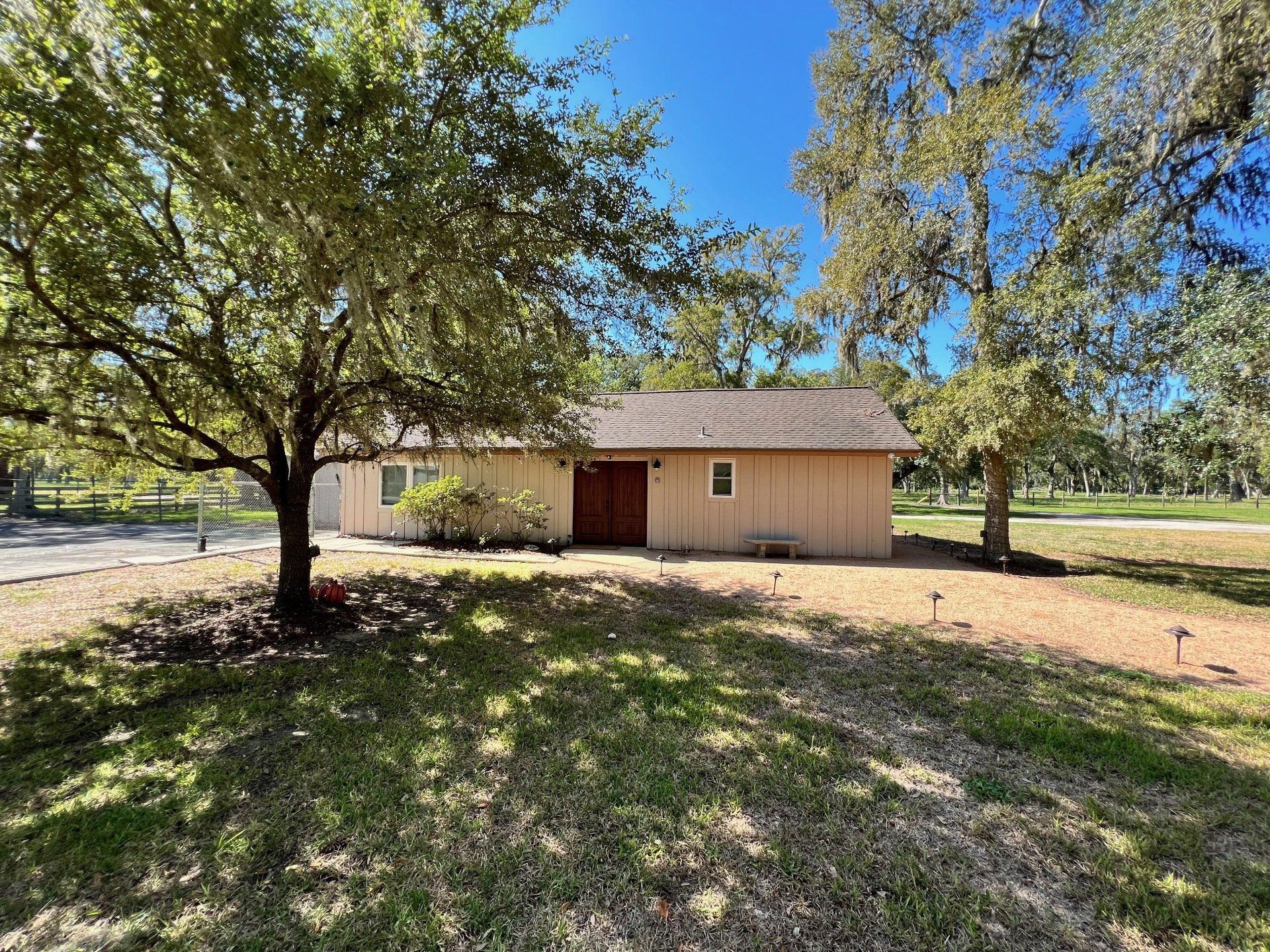 a small house is sitting in the middle of a grassy field surrounded by trees .