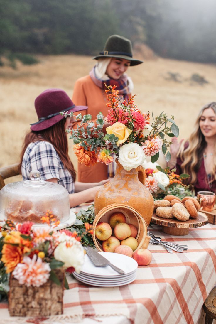 a group of women are sitting at a table with a vase of flowers on it .