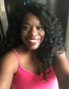 a woman in a pink tank top is smiling and taking a selfie .