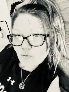 a black and white photo of a woman wearing glasses and a necklace .