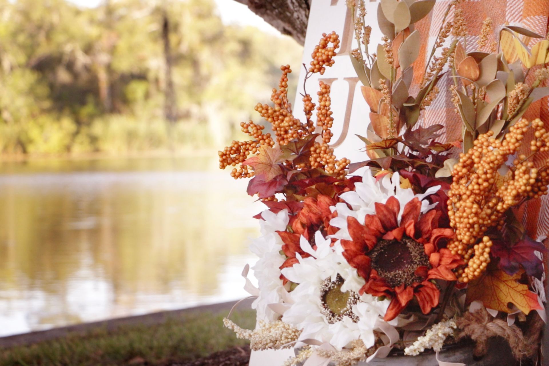 a wreath with flowers and leaves is sitting in front of a lake .